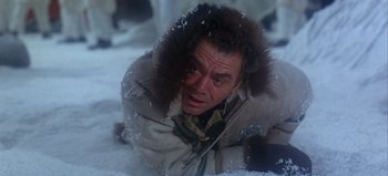 Movie still from “Ice Station Zebra” (1968), directed by John Sturges – A man in a fur lined coat laying in the snow; Close Up shot, High angle