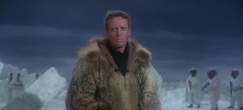 Movie still from “Ice Station Zebra” (1968), directed by John Sturges – A man in a fur coat standing in front of a snowy mountain; Medium shot, Low angle