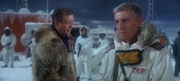 Movie still from “Ice Station Zebra” (1968), directed by John Sturges – Two men are standing in the middle of a snowy field; Medium shot, Low angle