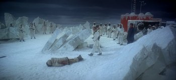 Movie still from “Ice Station Zebra” (1968), directed by John Sturges – A painting of a group of men in white suits standing in the snow next to a dead body; Extreme Wide shot, High angle