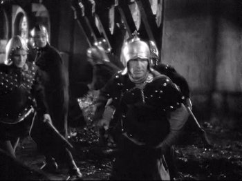 Movie still from “If I Were King” (1938), directed by Frank Lloyd – A black and white photo of a group of men in helmets; Medium shot, High angle