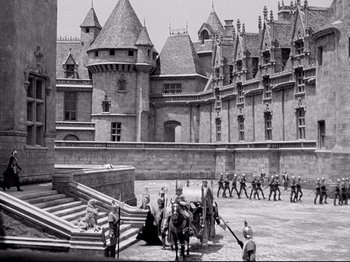Movie still from “If I Were King” (1938), directed by Frank Lloyd – A group of people standing in front of a castle; Extreme Wide shot, High angle
