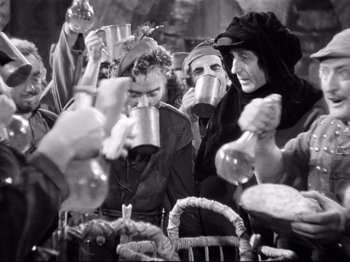 Movie still from “If I Were King” (1938), directed by Frank Lloyd – A black and white photo of a group of people drinking from cups; Medium shot, Low angle
