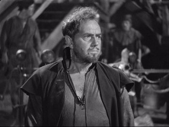 Movie still from “If I Were King” (1938), directed by Frank Lloyd – A man with a beard is standing in front of a group of people; Close Up shot, Over the shoulder angle