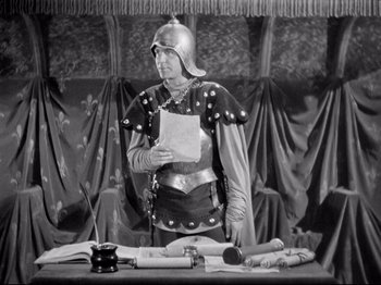 Movie still from “If I Were King” (1938), directed by Frank Lloyd – A man dressed as a roman soldier holding a paper; Medium shot, High angle