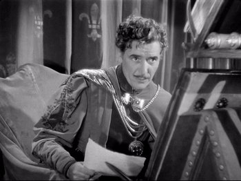 Movie still from “If I Were King” (1938), directed by Frank Lloyd – An old black and white photo of a man holding a piece of paper; Medium shot, High angle