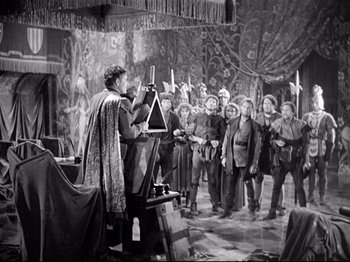Movie still from “If I Were King” (1938), directed by Frank Lloyd – An old photo of a group of people standing in a room; Wide shot, High angle