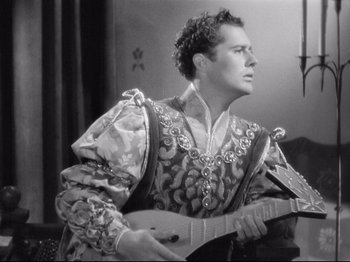 Movie still from “If I Were King” (1938), directed by Frank Lloyd – A black and white photo of a man holding a guitar; Medium shot, Low angle