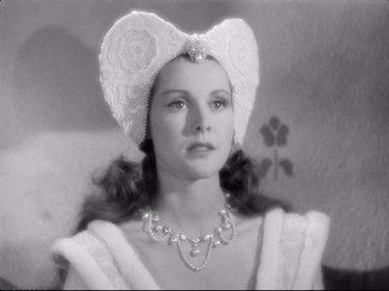 Movie still from “If I Were King” (1938), directed by Frank Lloyd – A young woman wearing an elaborate hat and a necklace; Close Up shot, Over the shoulder angle