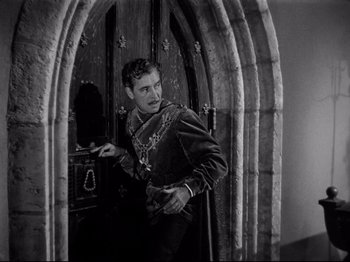 Movie still from “If I Were King” (1938), directed by Frank Lloyd – A young man in a medieval garb standing in front of an arched doorway; Medium shot, High angle