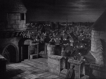 Movie still from “If I Were King” (1938), directed by Frank Lloyd – An image of a man standing on the roof of a building; Extreme Wide shot, High angle