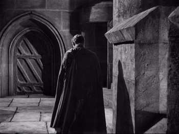 Movie still from “If I Were King” (1938), directed by Frank Lloyd – A man wearing a cape walking down a street; Wide shot, Over the shoulder angle