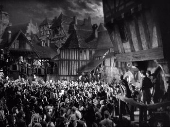 Movie still from “If I Were King” (1938), directed by Frank Lloyd – A crowd of people sitting in front of a building; Extreme Wide shot, High angle