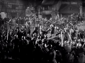 Movie still from “If I Were King” (1938), directed by Frank Lloyd – A black and white photo of a crowd of people with swords; Extreme Wide shot, High angle