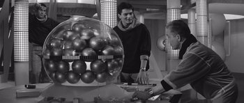 Movie still from “Voyage to the End of the Universe” (1963), directed by Jindrich Polák – A man standing in front of an object in a room; Medium shot, Over the shoulder angle