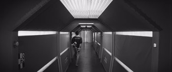 Movie still from “Voyage to the End of the Universe” (1963), directed by Jindrich Polák – A man walking down a long hallway in a building; Wide shot, Low angle