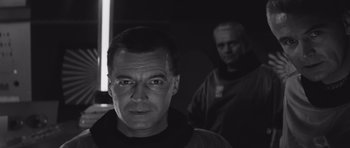 Movie still from “Voyage to the End of the Universe” (1963), directed by Jindrich Polák – A black - and - white photo of a man in a black shirt; Close Up shot, Low angle