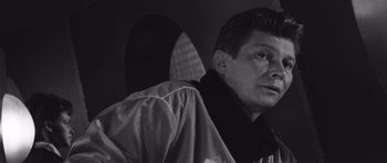 Movie still from “Voyage to the End of the Universe” (1963), directed by Jindrich Polák – Black and white photograph of a man looking at the camera; Close Up shot, Low angle