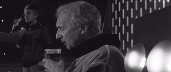 Movie still from “Voyage to the End of the Universe” (1963), directed by Jindrich Polák – An older man wearing a black and white photo; Close Up shot, Low angle