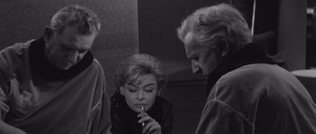 Movie still from “Voyage to the End of the Universe” (1963), directed by Jindrich Polák – A woman sitting on the ground with two men; Medium shot, High angle