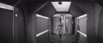 Movie still from “Voyage to the End of the Universe” (1963), directed by Jindrich Polák – A black and white photo of a woman walking in an elevator; Wide shot, Low angle