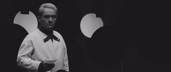 Movie still from “Voyage to the End of the Universe” (1963), directed by Jindrich Polák – A black and white photo of a man holding a martini glass; Medium shot, Low angle