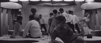 Movie still from “Voyage to the End of the Universe” (1963), directed by Jindrich Polák – A group of people standing around a room; Wide shot, High angle