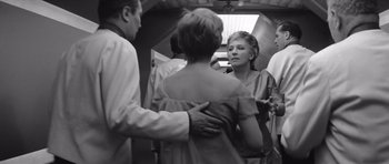 Movie still from “Voyage to the End of the Universe” (1963), directed by Jindrich Polák – A group of people standing next to each other on a train; Medium shot, Over the shoulder angle
