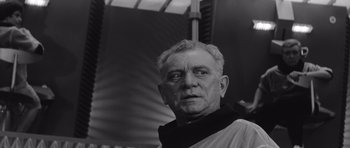 Movie still from “Voyage to the End of the Universe” (1963), directed by Jindrich Polák – An older man wearing a black and white photo; Close Up shot, Low angle