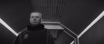 Movie still from “Voyage to the End of the Universe” (1963), directed by Jindrich Polák – A black and white photo of a man wearing a monk's robe; Close Up shot, Low angle