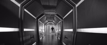 Movie still from “Voyage to the End of the Universe” (1963), directed by Jindrich Polák – A person is walking down a hallway in a building; Wide shot, Low angle