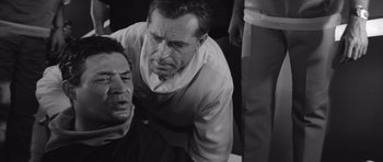 Movie still from “Voyage to the End of the Universe” (1963), directed by Jindrich Polák – Two men in black and white one of them is lying on the ground and the other is looking down; Close Up shot, Over the shoulder angle