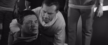 Movie still from “Voyage to the End of the Universe” (1963), directed by Jindrich Polák – Two men are sitting on the ground and one is looking at the camera; Close Up shot, Over the shoulder angle