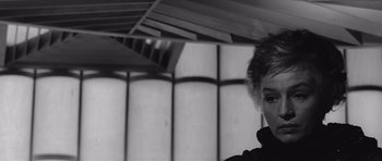 Movie still from “Voyage to the End of the Universe” (1963), directed by Jindrich Polák – A black and white photo of a woman in front of a building; Close Up shot, Low angle