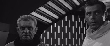 Movie still from “Voyage to the End of the Universe” (1963), directed by Jindrich Polák – A black and white photo of a man standing in front of a wall; Close Up shot, Low angle