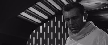 Movie still from “Voyage to the End of the Universe” (1963), directed by Jindrich Polák – A black and white photo of a man in a white shirt; Close Up shot, Low angle