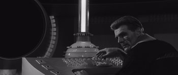 Movie still from “Voyage to the End of the Universe” (1963), directed by Jindrich Polák – A man sitting in front of a computer keyboard; Medium shot, Low angle
