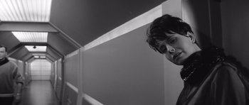 Movie still from “Voyage to the End of the Universe” (1963), directed by Jindrich Polák – A man standing next to a white wall in a room; Close Up shot, Low angle