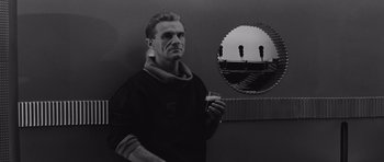 Movie still from “Voyage to the End of the Universe” (1963), directed by Jindrich Polák – A black and white photo of a man in front of a mirror; Medium shot, Low angle