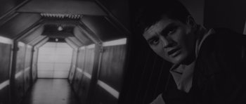 Movie still from “Voyage to the End of the Universe” (1963), directed by Jindrich Polák – A black - and - white photo of a young man in front of a wall; Close Up shot, Low angle