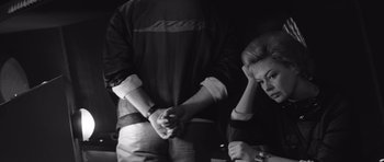 Movie still from “Voyage to the End of the Universe” (1963), directed by Jindrich Polák – Two people holding hands in a dark room; Medium shot, Over the shoulder angle