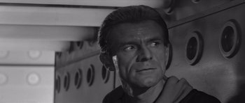 Movie still from “Voyage to the End of the Universe” (1963), directed by Jindrich Polák – Black and white photograph of a man looking at the camera; Close Up shot, Low angle
