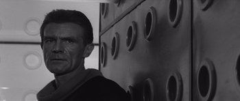 Movie still from “Voyage to the End of the Universe” (1963), directed by Jindrich Polák – A black and white photo of a man in front of a wall; Close Up shot, Low angle
