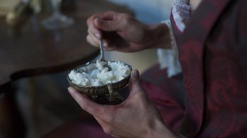 Movie still from “The Bohemian” (2022), directed by Petr Václav – A person holding a bowl of rice with a spoon in it; Extreme Close Up shot, High angle