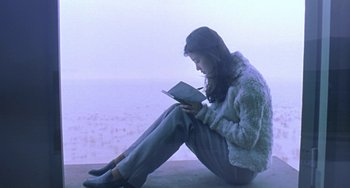 Movie still from “Il Mare” (2000), directed by Hyun-seung Lee – A woman sitting on the ground while reading a book; Medium shot, Low angle
