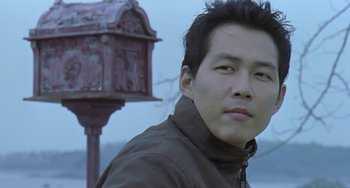 Movie still from “Il Mare” (2000), directed by Hyun-seung Lee – A man in a brown jacket standing in front of a street light; Close Up shot, Low angle