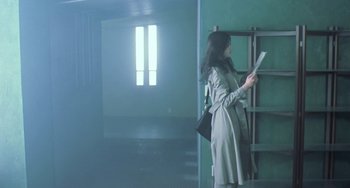 Movie still from “Il Mare” (2000), directed by Hyun-seung Lee – A woman standing in front of a window holding a book; Wide shot, Low angle