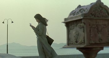 Movie still from “Il Mare” (2000), directed by Hyun-seung Lee – A woman walking on the beach while looking at her cell phone; Wide shot, Low angle