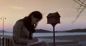 Movie still from “Il Mare” (2000), directed by Hyun-seung Lee – A woman sitting on a bench writing in a notebook; Medium shot, Low angle