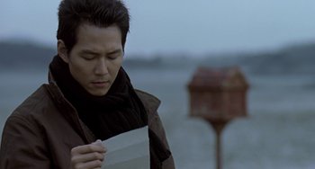 Movie still from “Il Mare” (2000), directed by Hyun-seung Lee – A man holding a piece of paper while standing in the rain; Close Up shot, Low angle